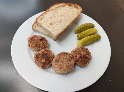 Debrecínska pečienka servírovaná spolu s kyslými uhorkami a čerstvým chlebom